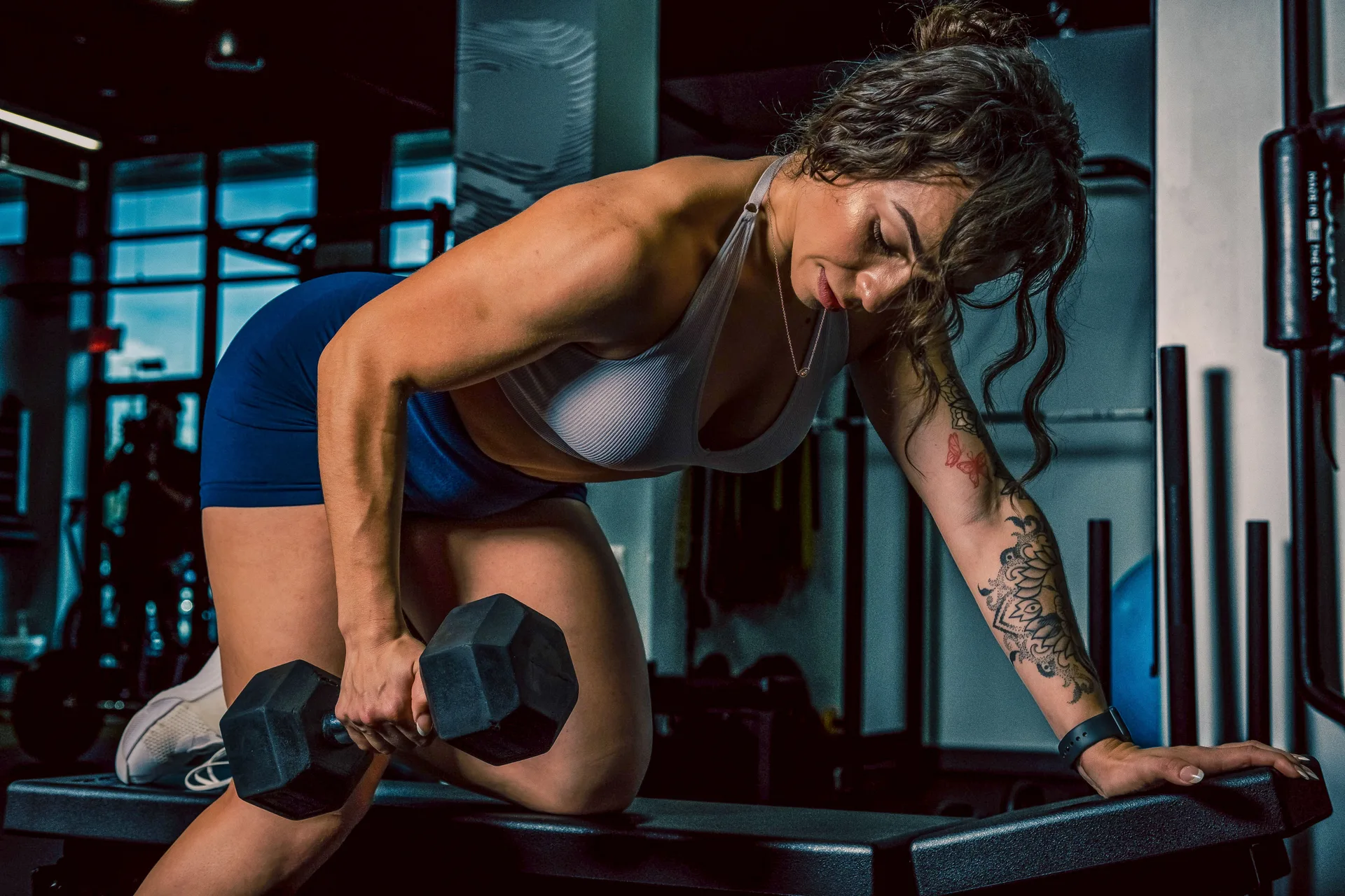 Focused woman lifting dumbbell for gym training. Intense and powerful workout session