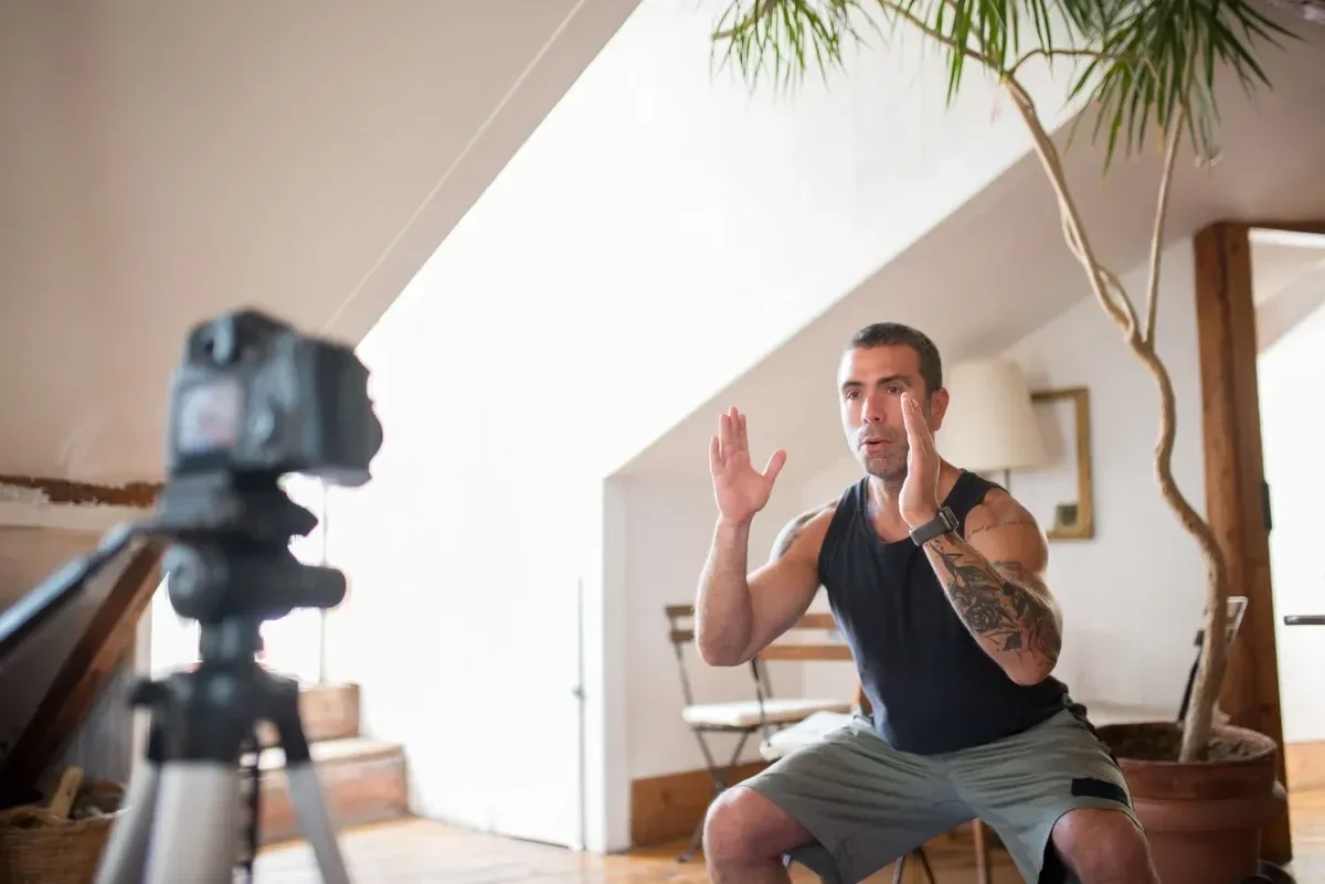 Male trainer filming a workout video indoors, focusing on exercise technique
