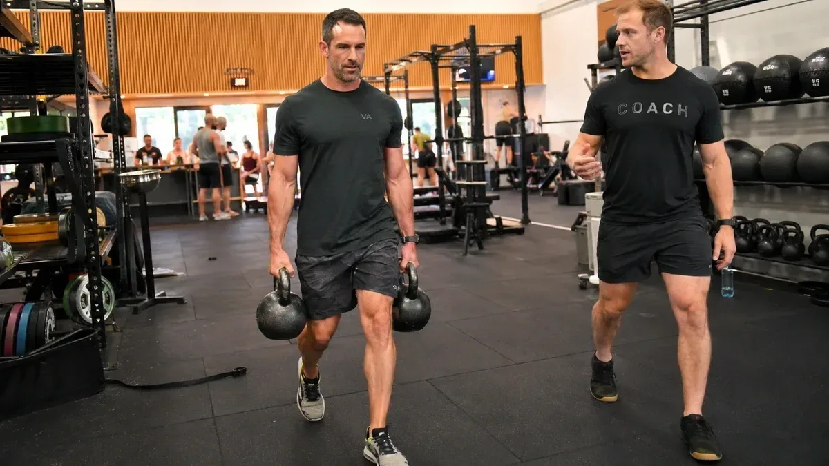 personal trainer training a male client in a busy gym
