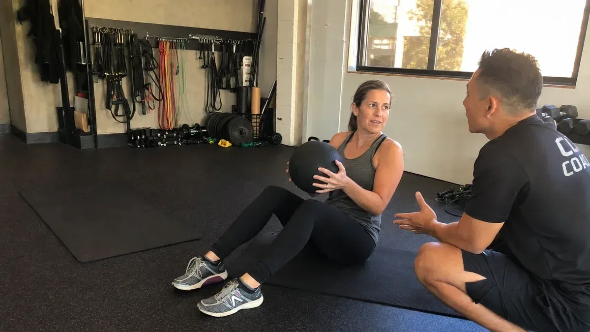 undefined personal trainer teaching female client to do core exercise