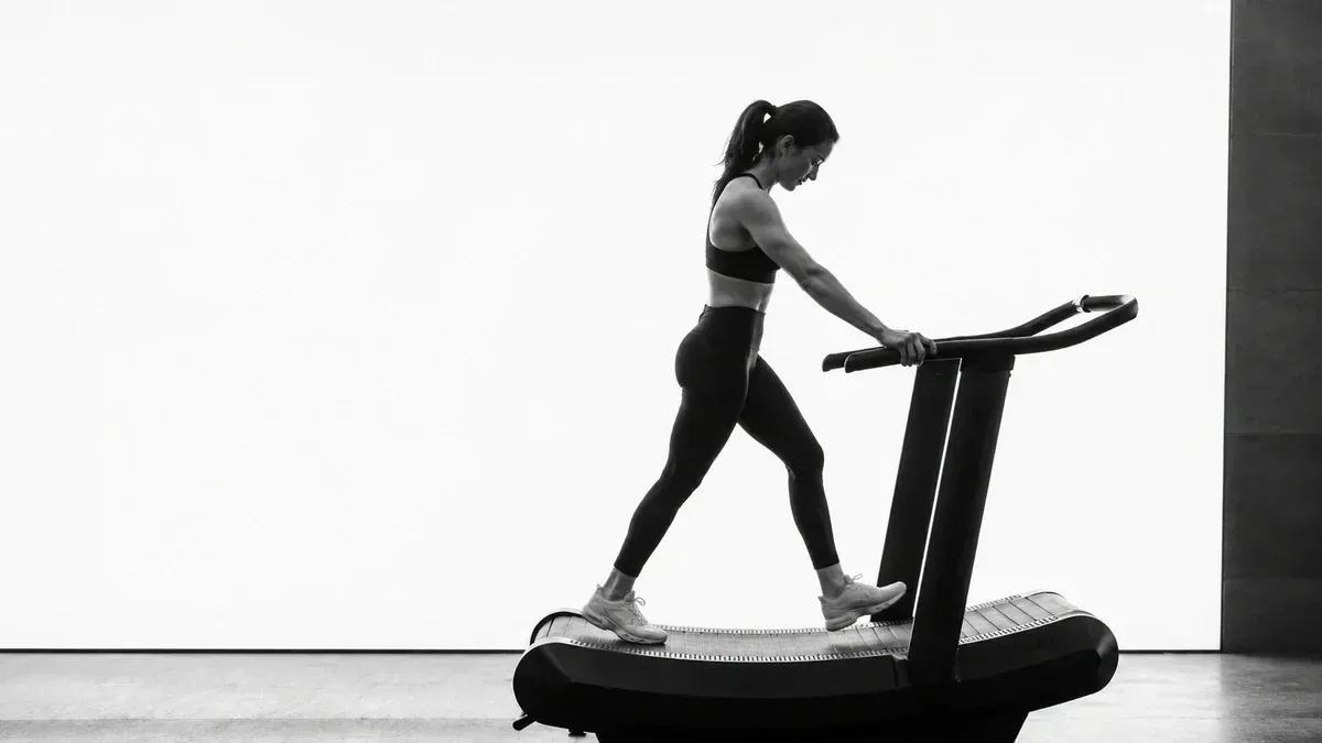 black and white image of a fit female personal trainer walking on a treadmill